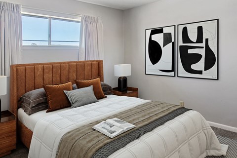 A bedroom with a large bed and two abstract art pieces on the wall.