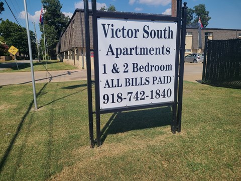 A sign for Victor South Apartments with a phone number on it.