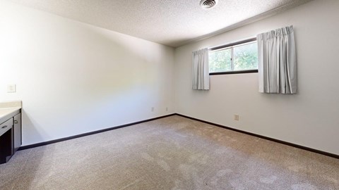 A room with a window and a carpeted floor.