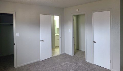 a bedroom with three doors and a carpeted floor
