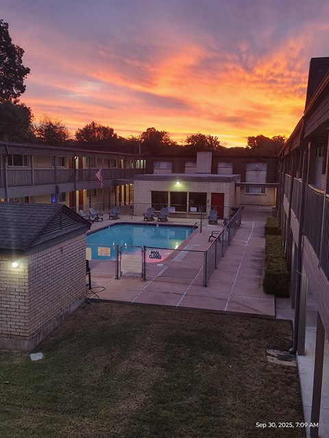 A pool with a fence and a building behind it.