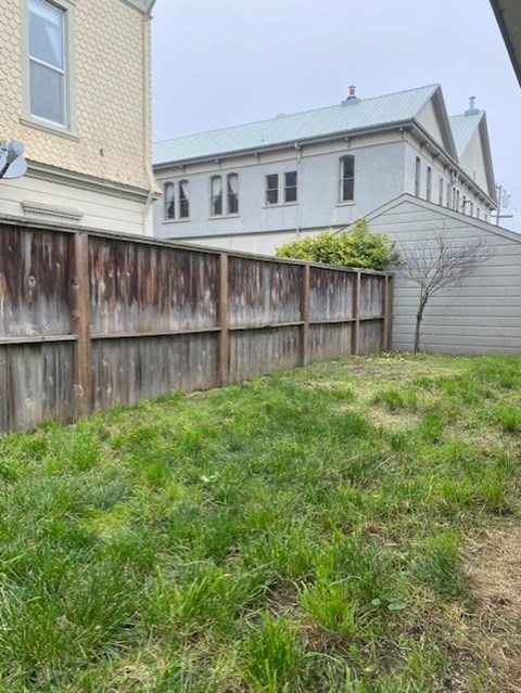 A wooden fence separates a grassy area from a building.