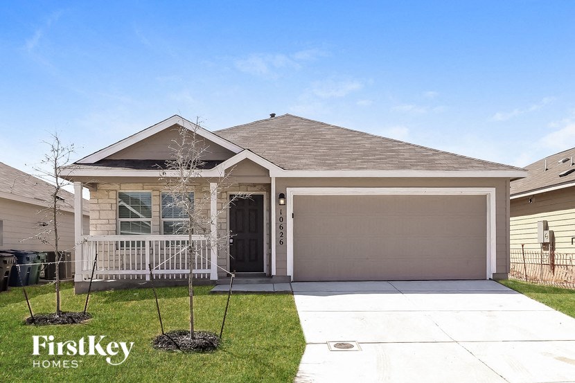 A house with a garage and a tree in front of it.