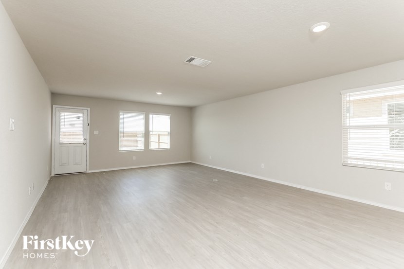 A spacious empty room with wooden flooring and white walls.