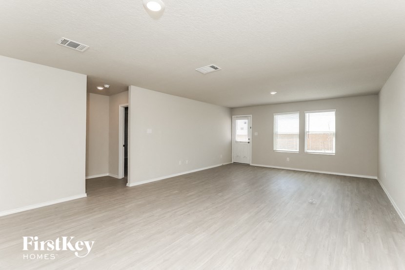 A spacious empty room with light wood flooring and white walls.