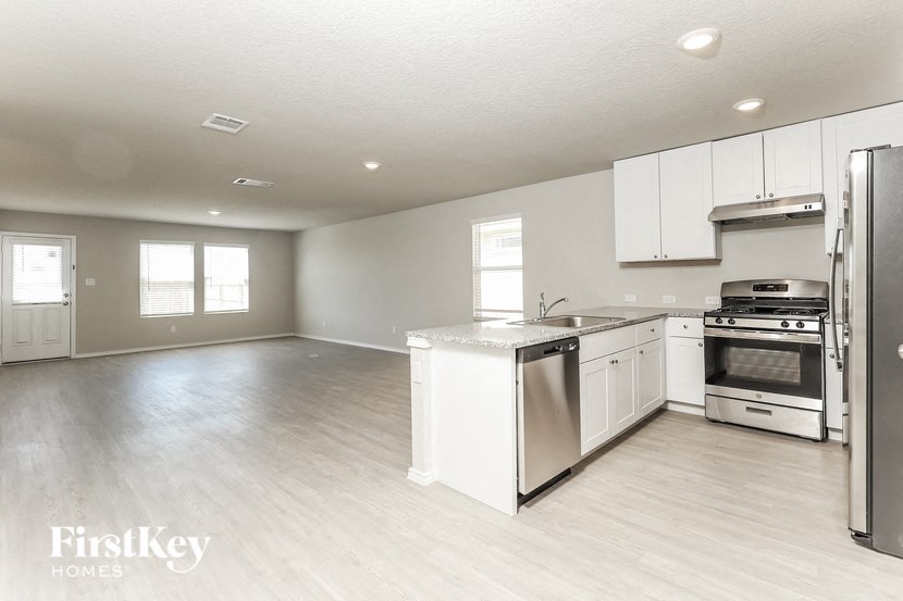 A kitchen with white appliances and wooden floors.