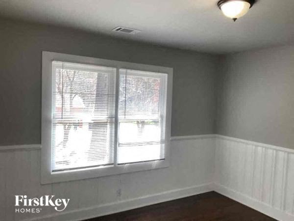 an empty room with a window and a lamp on the ceiling