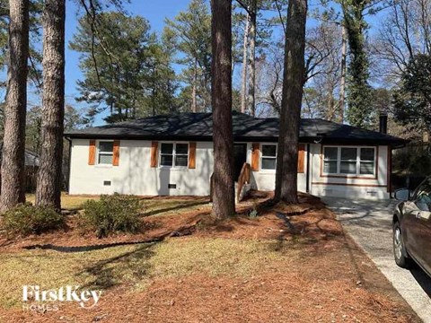 a small white house in the woods with tall trees