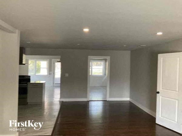 an empty living room and kitchen with white walls and wood floors