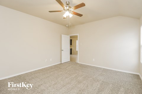 a spacious living room with carpet and a ceiling fan