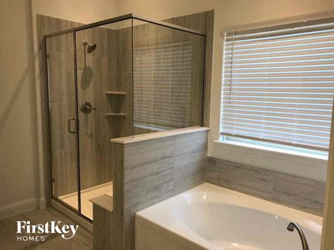 A white bathtub sits next to a window in a bathroom.