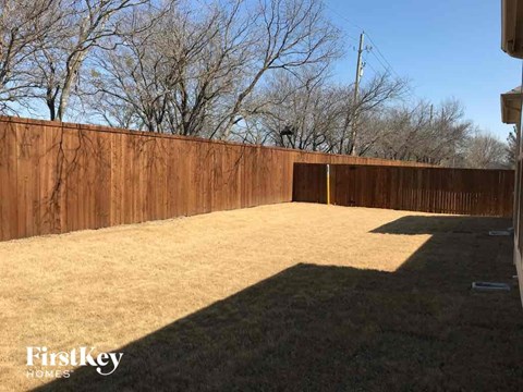 A backyard with a wooden fence and trees in the background.