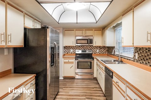 A kitchen with a black refrigerator and wooden cabinets.