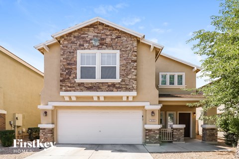 A house with a garage and a stone wall on the upper floor.