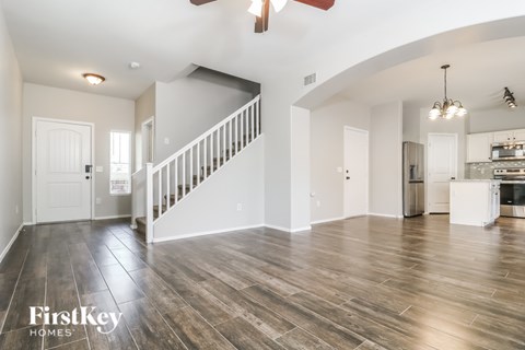 A spacious living room with wood flooring and a staircase leading to the upper level.