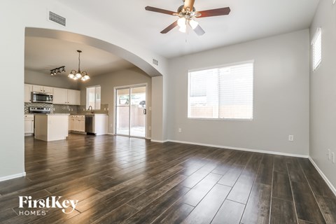 A spacious living room with a wood floor and a ceiling fan.