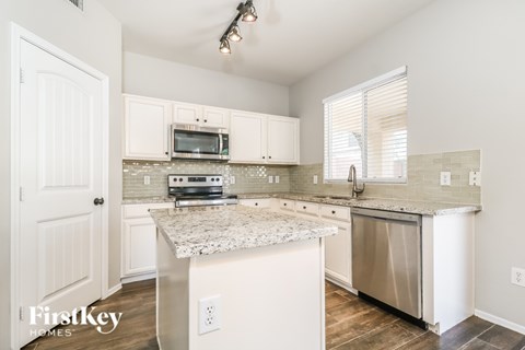 A kitchen with a granite countertop and stainless steel appliances.