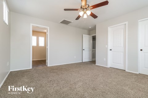 A spacious room with a ceiling fan and beige carpeting.