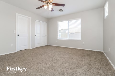 A room with a ceiling fan and carpeted floor.