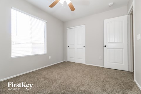 A room with a carpeted floor and two white doors.