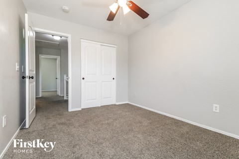 A spacious room with a ceiling fan and two doors.