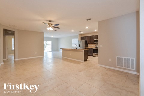 A spacious kitchen and living room with a tiled floor and a ceiling fan.
