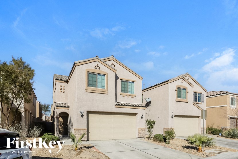 A beige house with a garage door and a window is for sale.