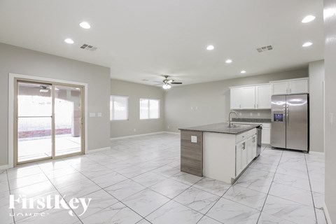 A spacious kitchen with a refrigerator, sink, and cabinets.