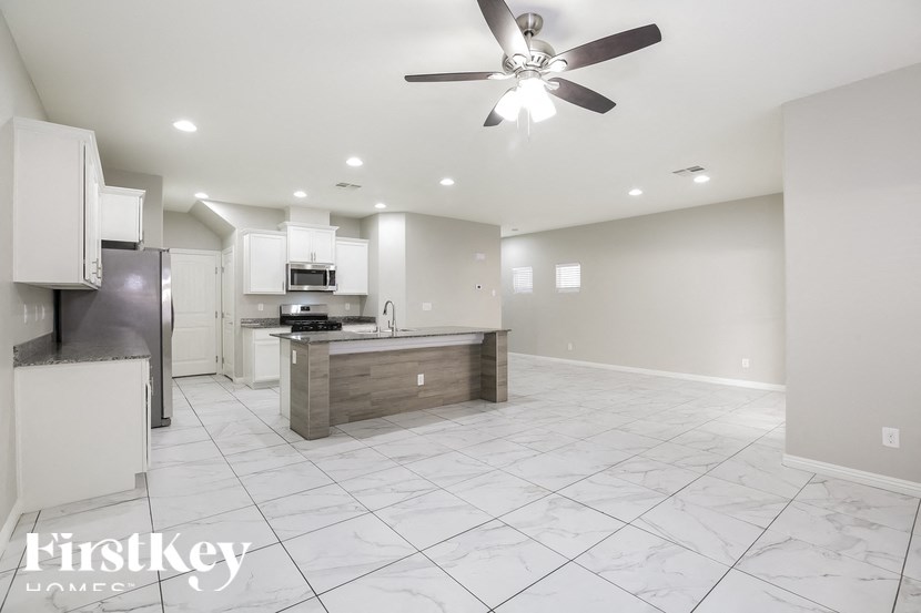 A spacious kitchen with a marble floor and a ceiling fan.