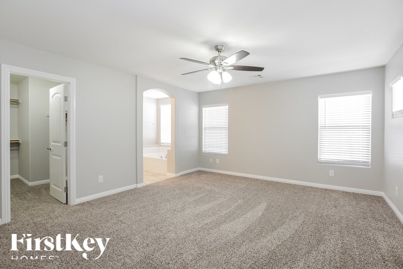 A spacious room with a carpeted floor and a ceiling fan.