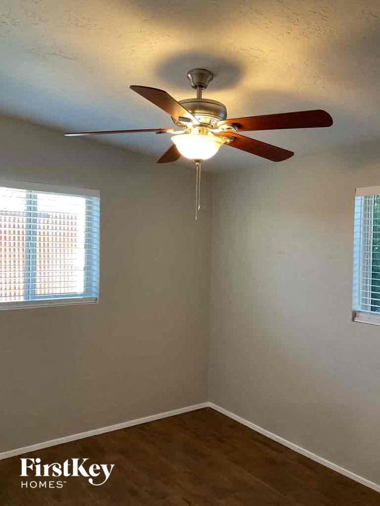 A room with a ceiling fan and two windows.