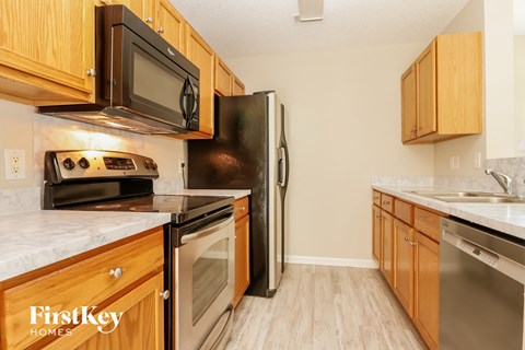 A kitchen with wooden cabinets and a black refrigerator.
