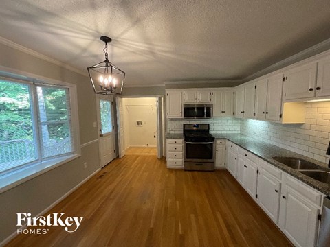 A kitchen with wooden floors and white cabinets.