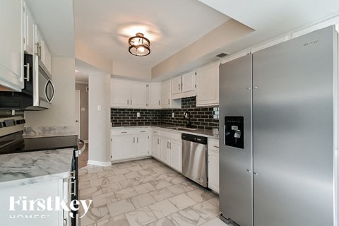 A kitchen with a stainless steel refrigerator and white cabinets.