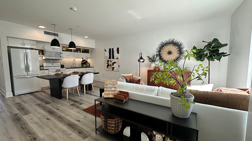 a kitchen and living room with white walls and wood floors at Idea1 Apartments in San Diego CA