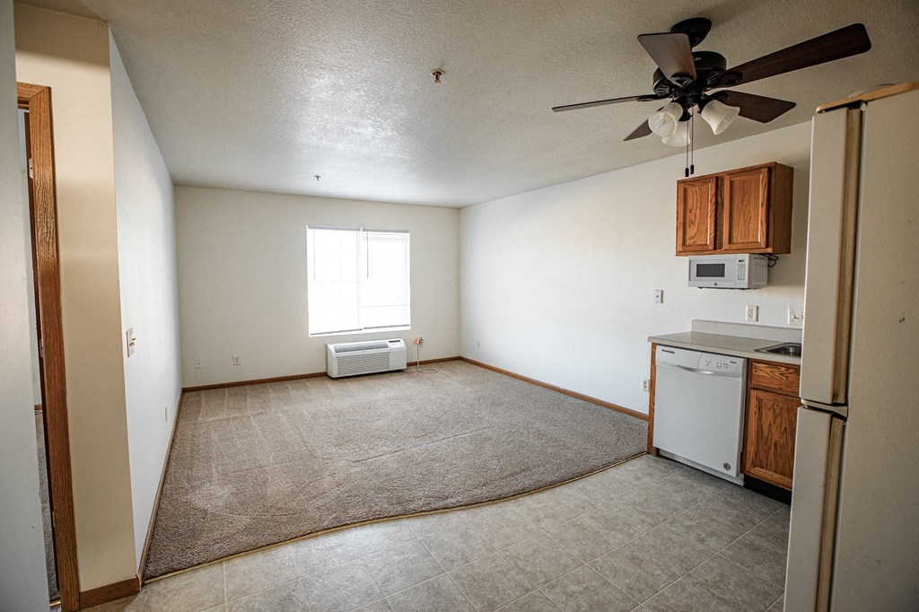 A small, empty room with a window, a fan, and a washer and dryer.