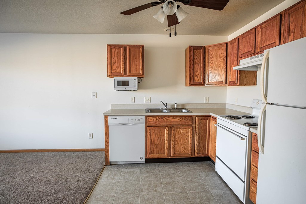 A kitchen with white appliances and wooden cabinets.
