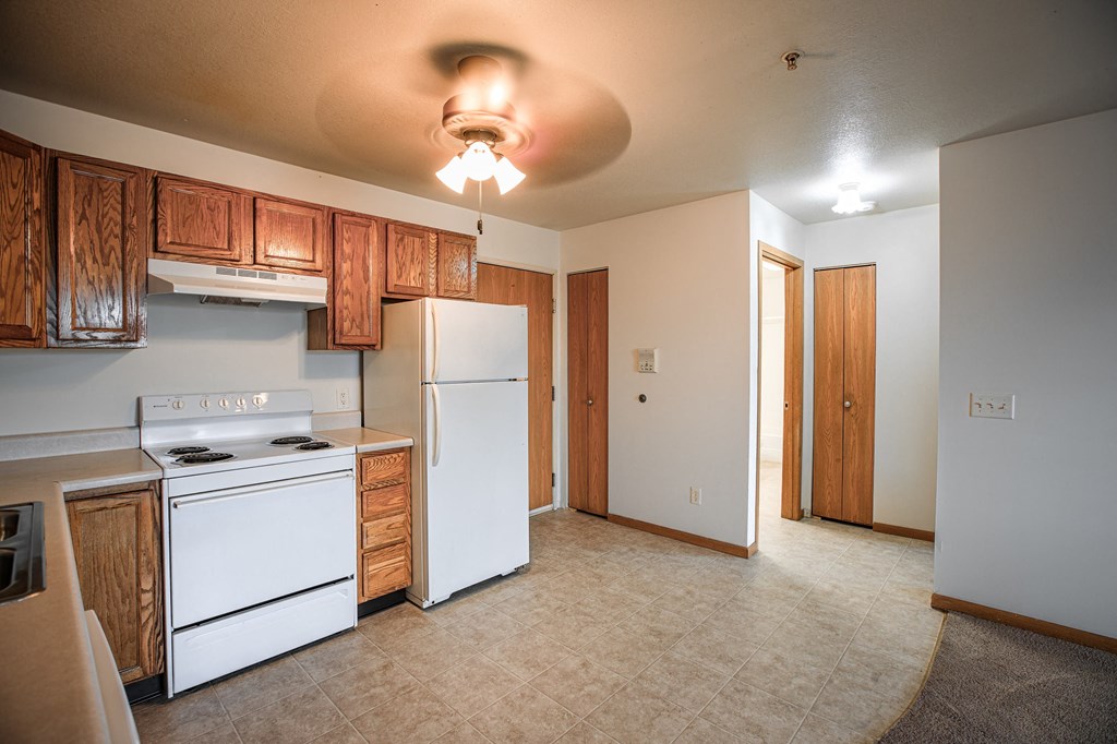 A kitchen with white appliances and wooden cabinets.