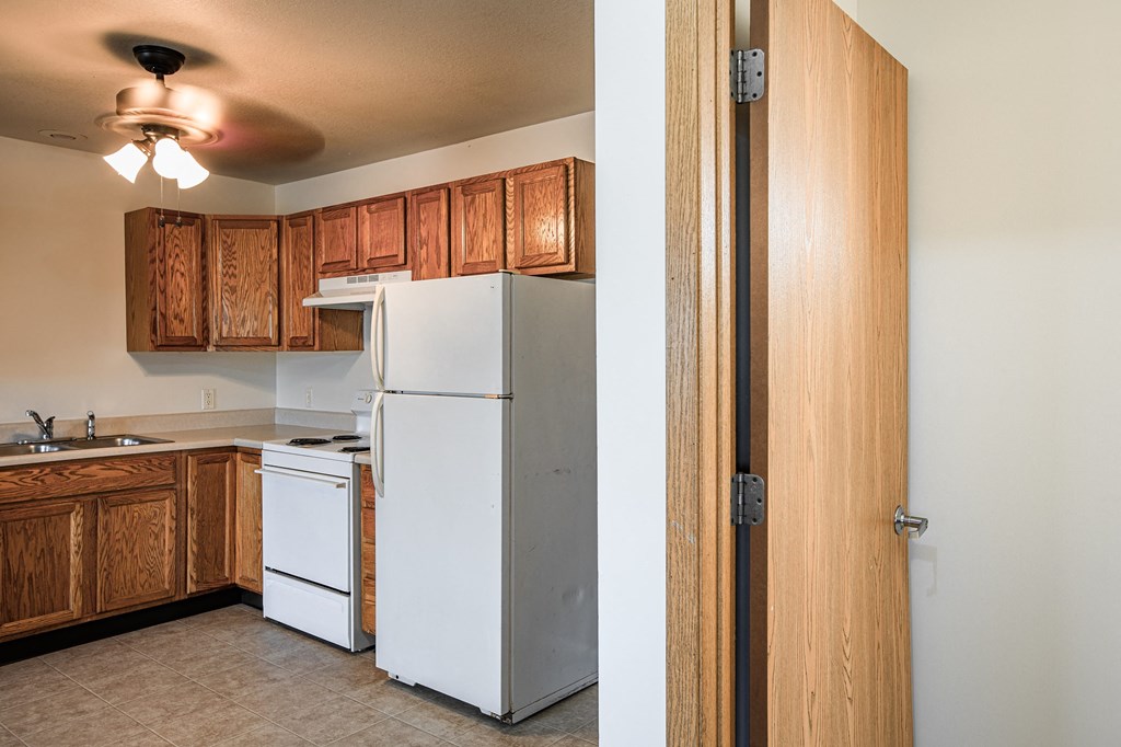 A white refrigerator in a kitchen with wooden cabinets.