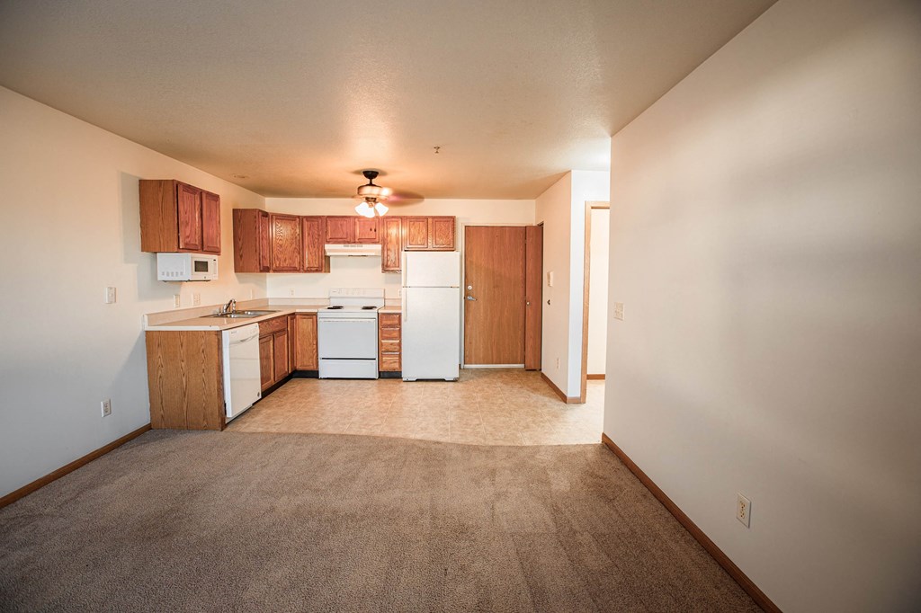 A kitchen with white appliances and wooden cabinets.