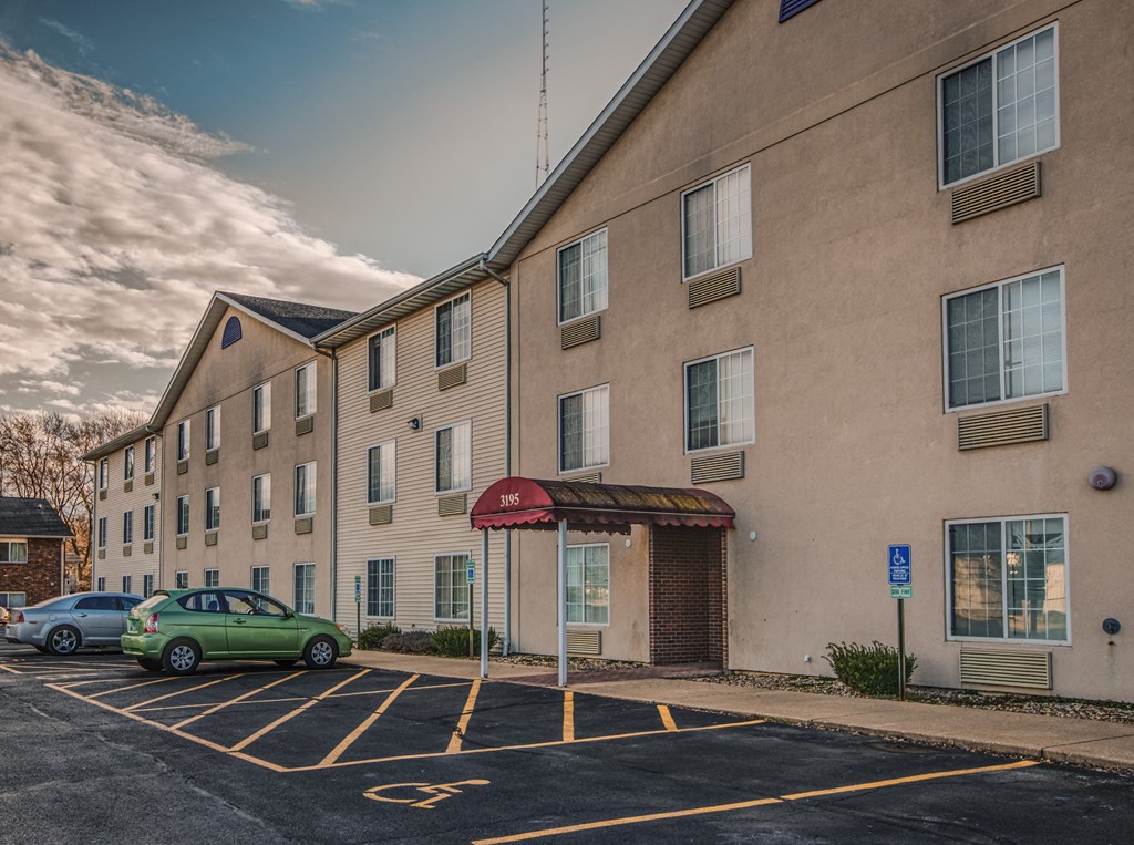 A parking lot in front of a building with cars parked.