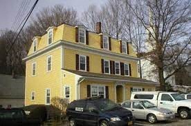 a yellow house with cars parked in front of it