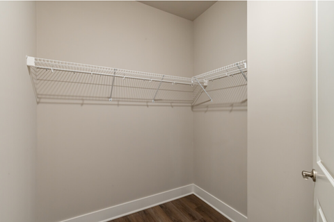 the closet in a bedroom of a home with white shelves and a white door
