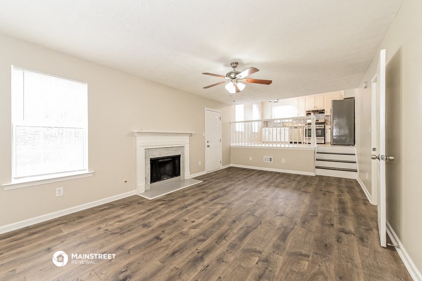 an empty living room with a fireplace and a ceiling fan