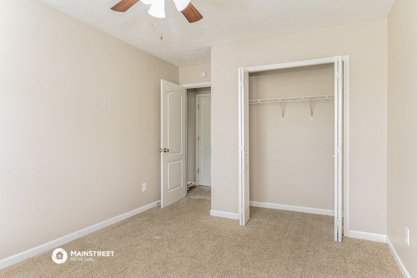 an empty bedroom with a closet and a ceiling fan