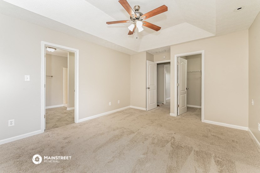 a spacious living room with carpet and a ceiling fan