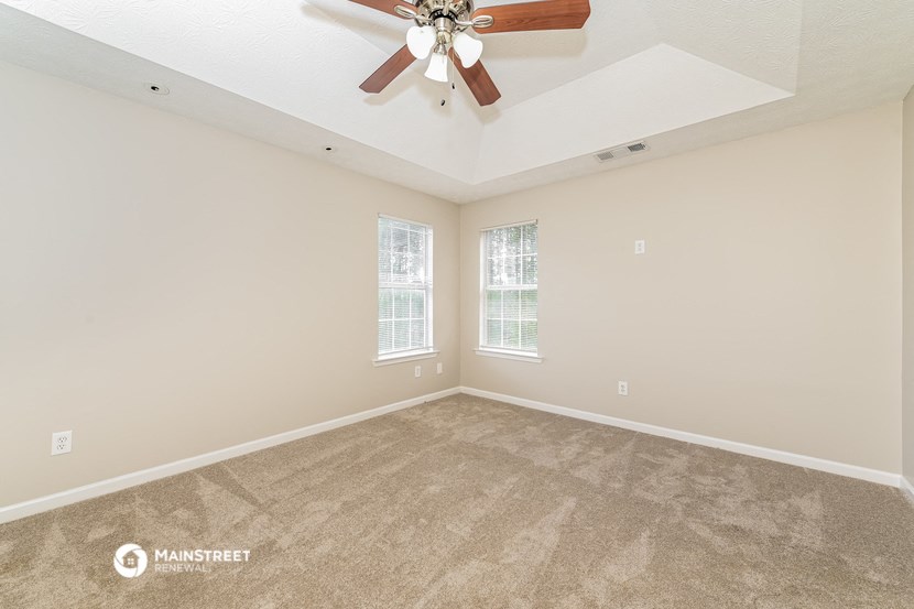 a living room with carpet and a ceiling fan