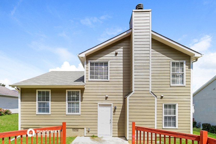 a tan house with a red fence in front of it