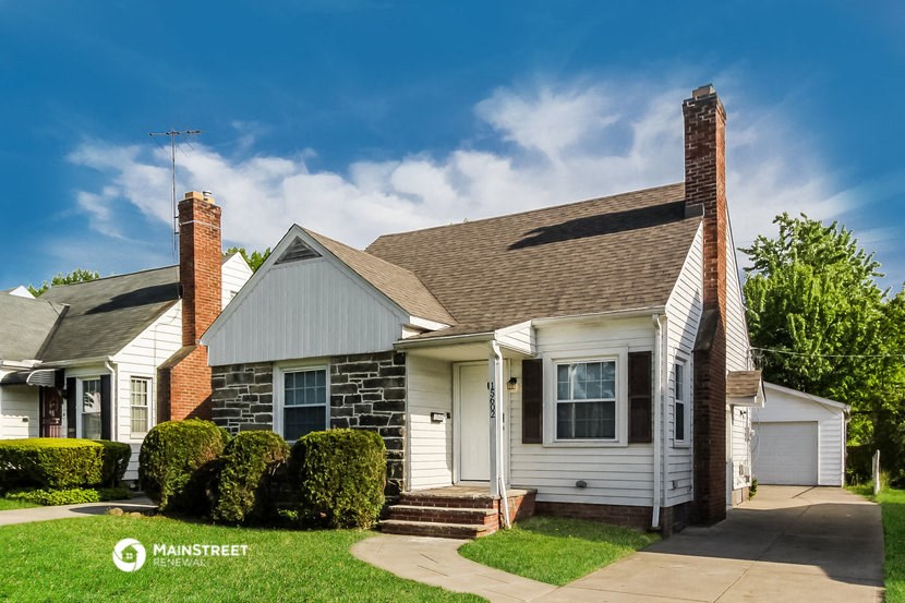 a small white house with a lawn and a blue sky