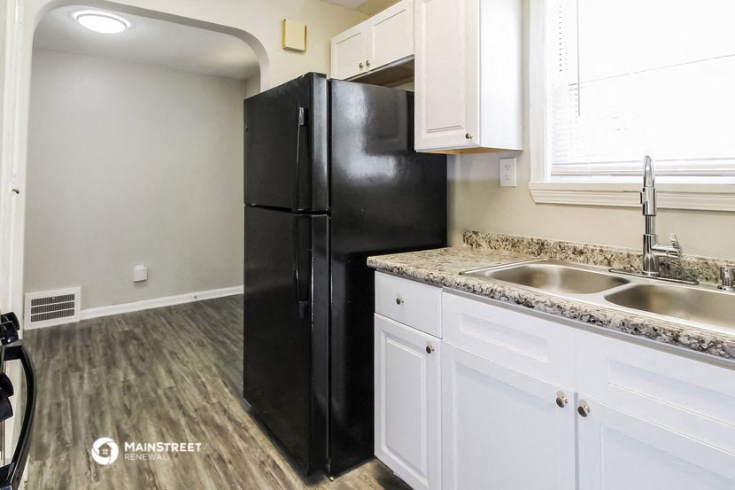 a kitchen with white cabinets and a black refrigerator